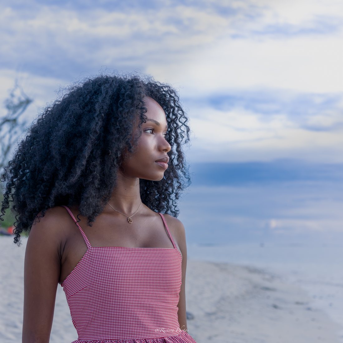 Jeune femme de profil au bord du lagon, le regard tourné vers le large.