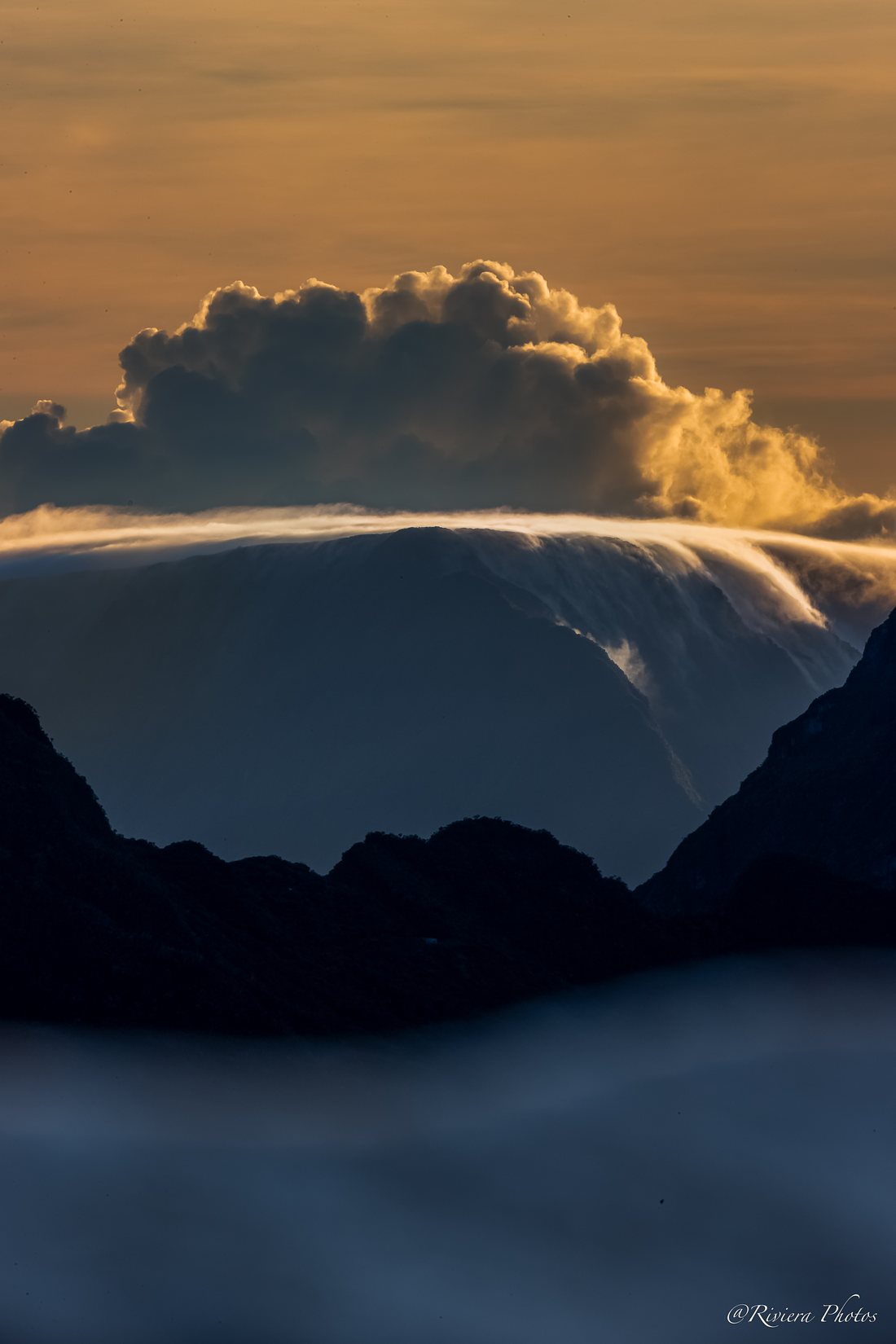 Nuage doré au-dessus d'une crête de montagne, mer de nuages en contrebas.